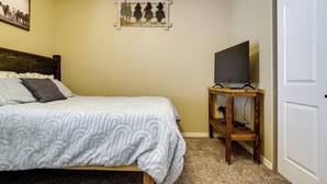 Ein Schlafzimmer mit einem Bett, einem Fernseher auf einem Holzständer und einer Tür.