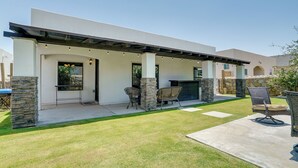 Eine moderne Außenpatio mit Steinpfeilern, einem überdachten Sitzbereich und einem Grill.