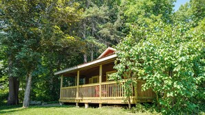 A wooden cabin with a porch, surrounded by dense greenery and trees. - 3 Mi to Hiking & Beaches: Rustic Maine Cabin (Stockton Springs)