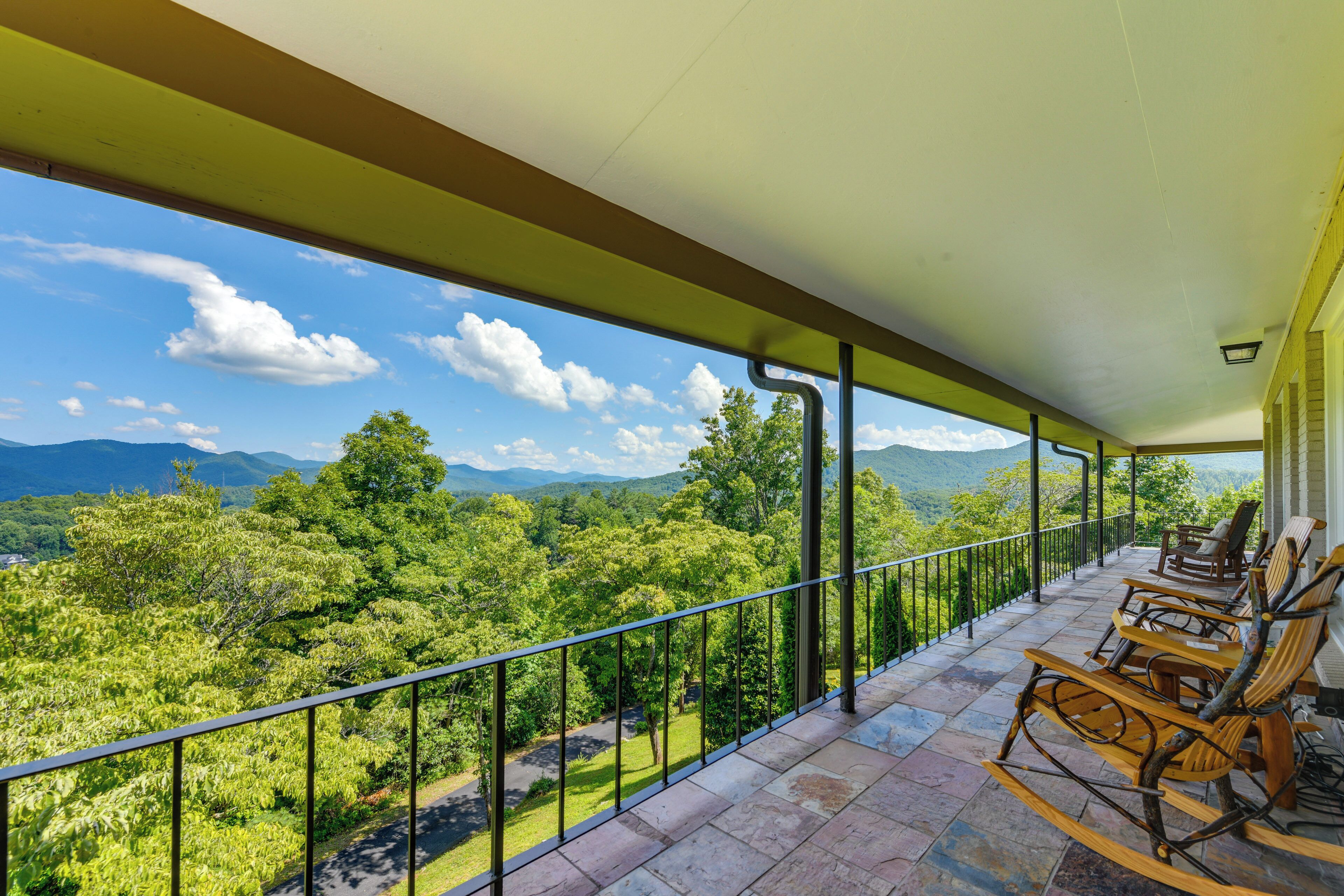 Ein Balkon mit Blick auf eine gebirgige Landschaft, Holzschaukelstühle und ein Fliesenboden.