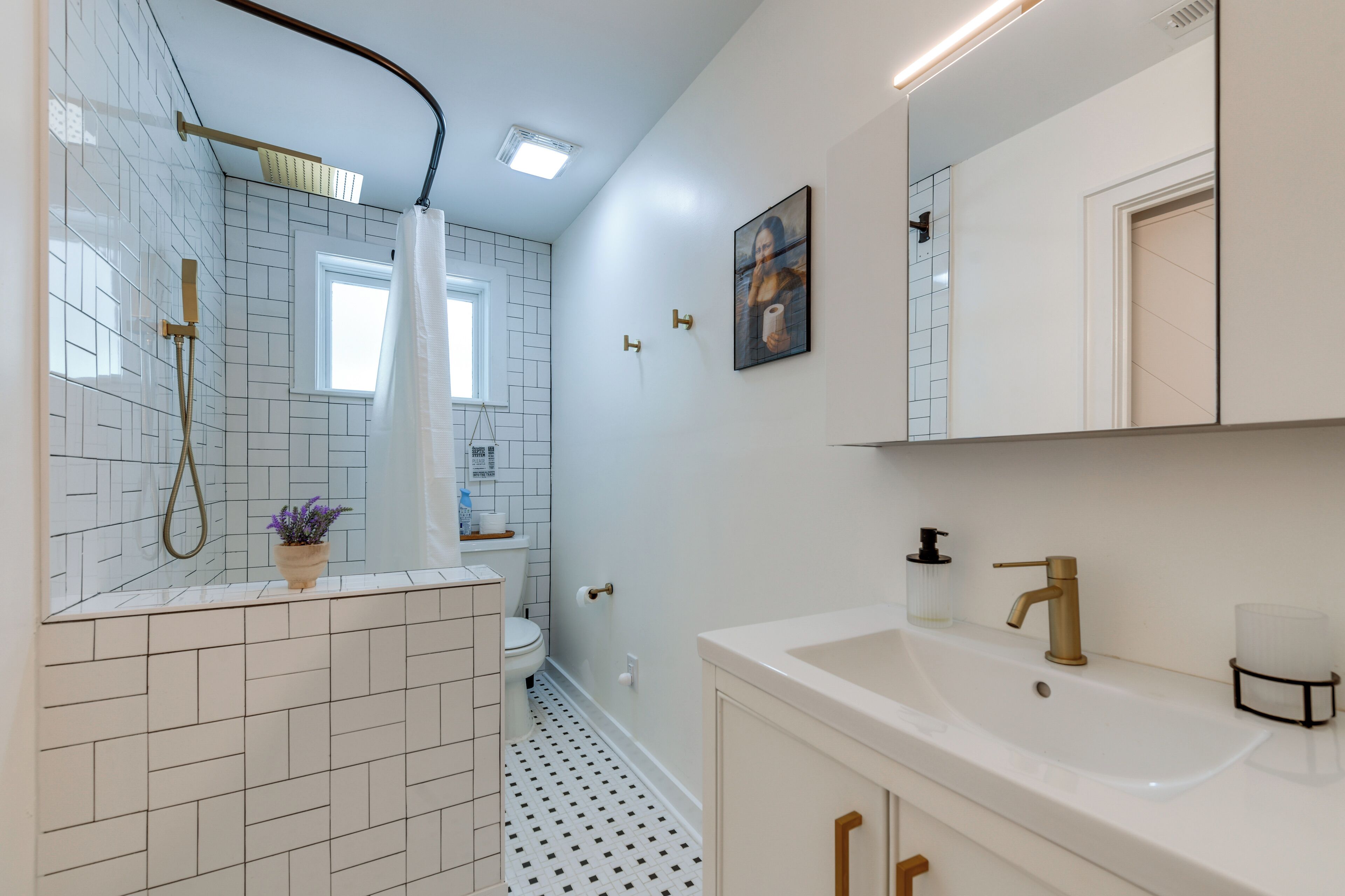 A modern bathroom with a shower, toilet, sink, and a mirror.