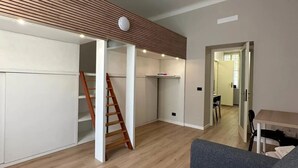 En modern inredning med ett loftliknande rum, trägolv, en trappa och en matplats.