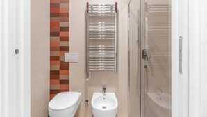 Une salle de bain moderne équipée de toilettes, d’un bidet et d’une douche à parois de verre.