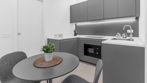Une cuisine moderne avec des meubles gris, un plan de travail blanc et un four encastré.