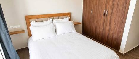 Een hotelkamer met een groot bed, een houten garderobe en een nachtkastje.