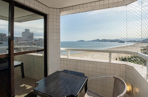 A balcony with a view of the beach, a table, and a chair. - SHB Beachfront Varanda e Piscina (Santos)