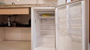 Un refrigerador abierto con estantes, un compartimento congelador y un dispensador de agua.