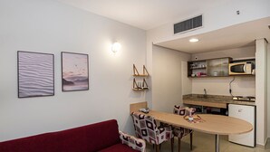 Un espacio habitable compacto con comedor, kitchenette y un sofá rojo.