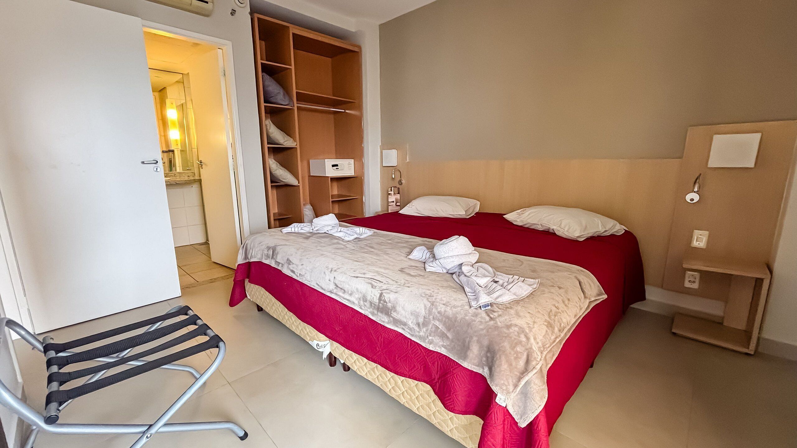 Una habitación de hotel con dos camas, un armario, un escritorio y una silla.