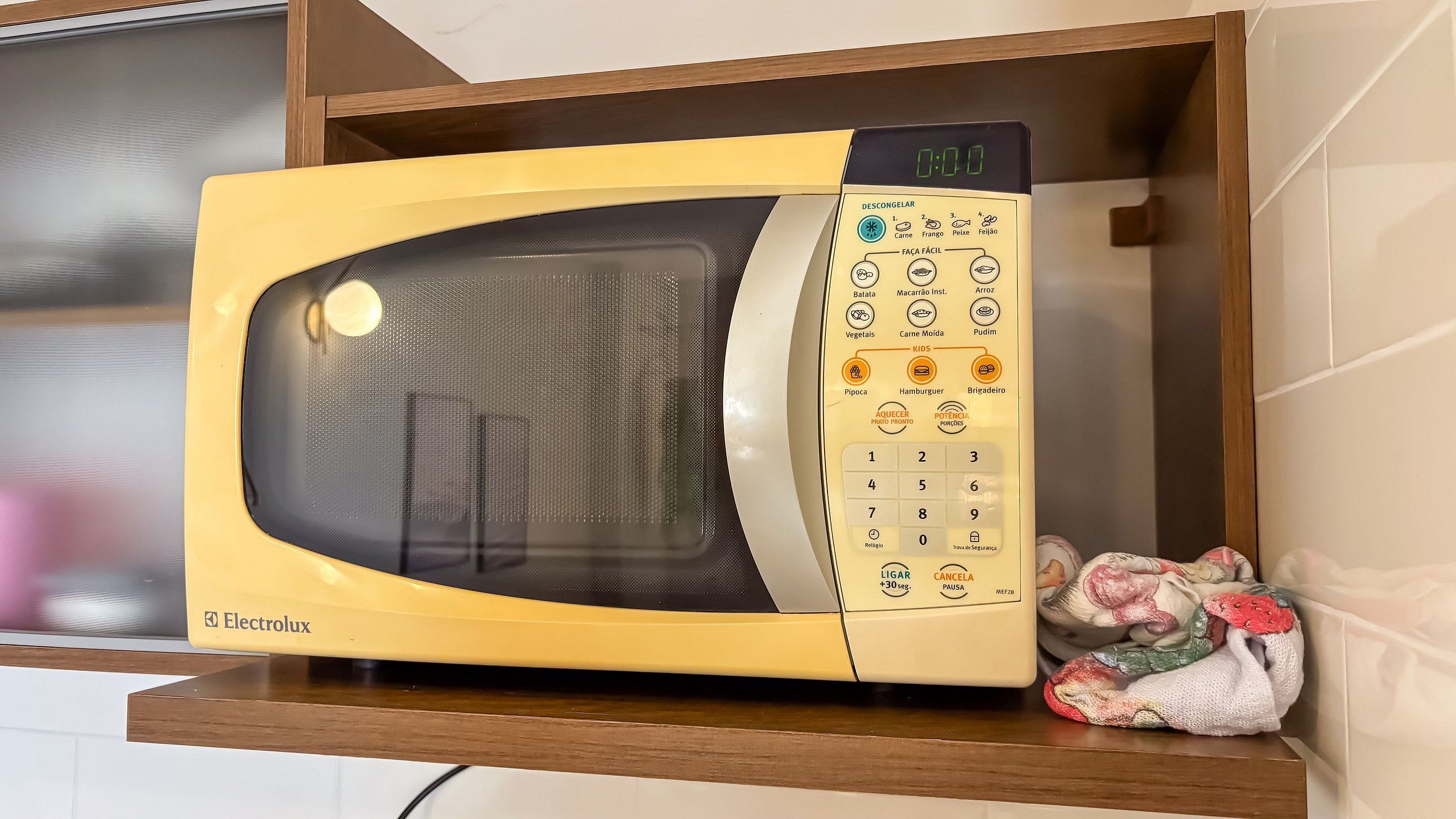 A yellow Electrolux microwave oven with a digital clock and a control panel with various cooking options.