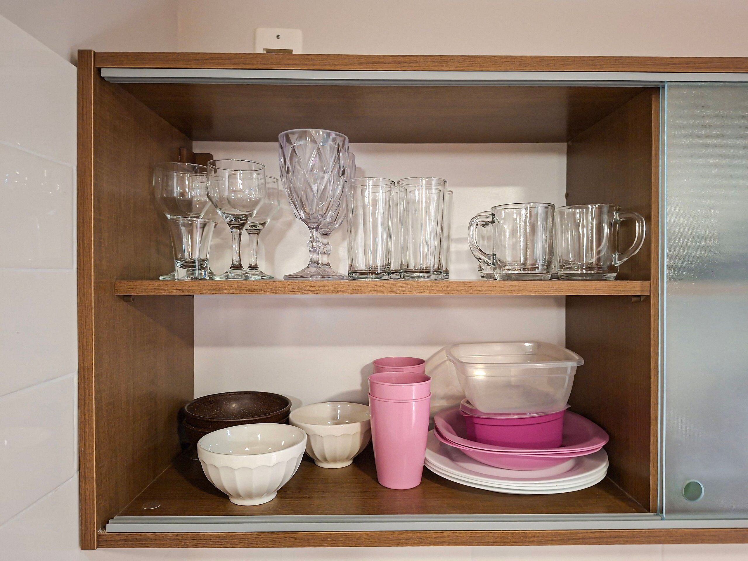 A wooden shelf unit with glassware and bowls.
