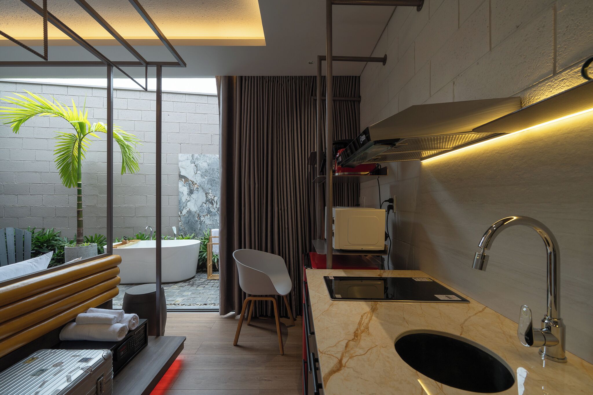 Een moderne badkamer met een badkuip, een wastafel, een stoel en een houten bankje.