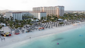 Um resort com área de praia, vários edifícios de hotel e uma praia arenosa com guarda-sóis.