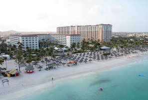 A resort with a beachfront, multiple hotel buildings, and a sandy beach with umbrellas.