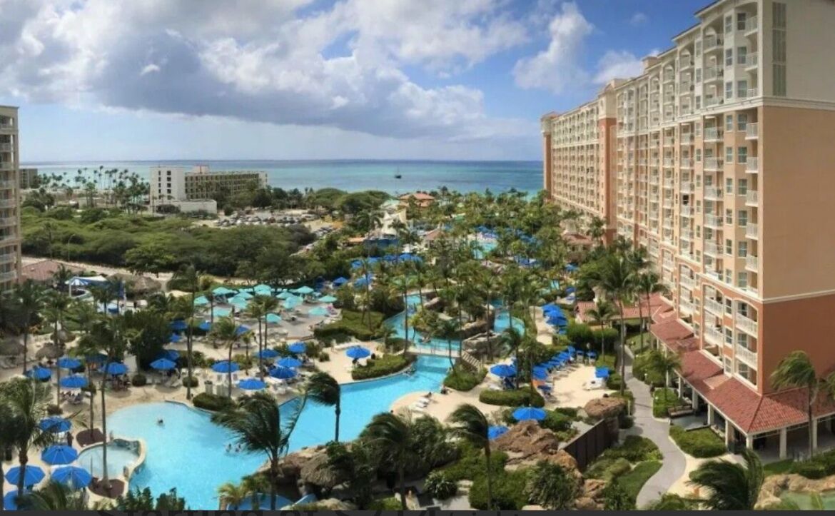 Un resort con varias piscinas, palmeras y vista al océano.