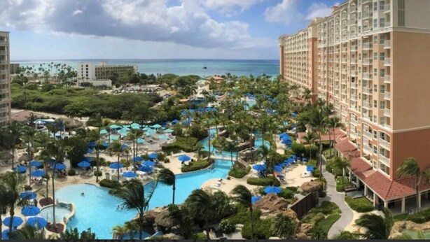 A resort with multiple swimming pools, palm trees, and a view of the ocean.
