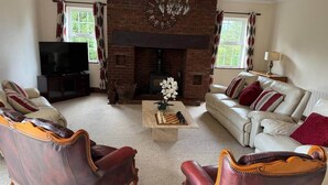 Una sala de estar con sillones de cuero, un sofá, una chimenea y un televisor.