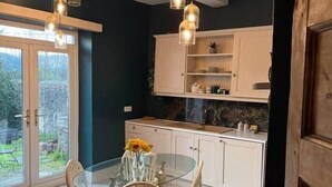 Una cocina moderna con mesa de comedor de vidrio, armarios blancos e iluminación colgante.
