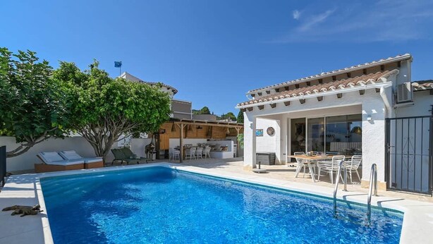 A swimming pool with a sun lounger and a covered patio area. - Boho Villa Montsalvat (Pego)