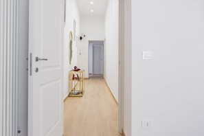 A hallway with white walls, a wooden floor, and a closed door on the left. - Santa Luciella Holiday Home  (Naples)