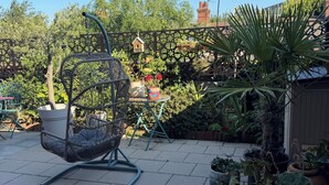 A patio with a wicker chair, potted plants, and a wooden fence. - Lovely 3-bedroom house in tranquil London perfect for your stay -sleeps 6 (London)