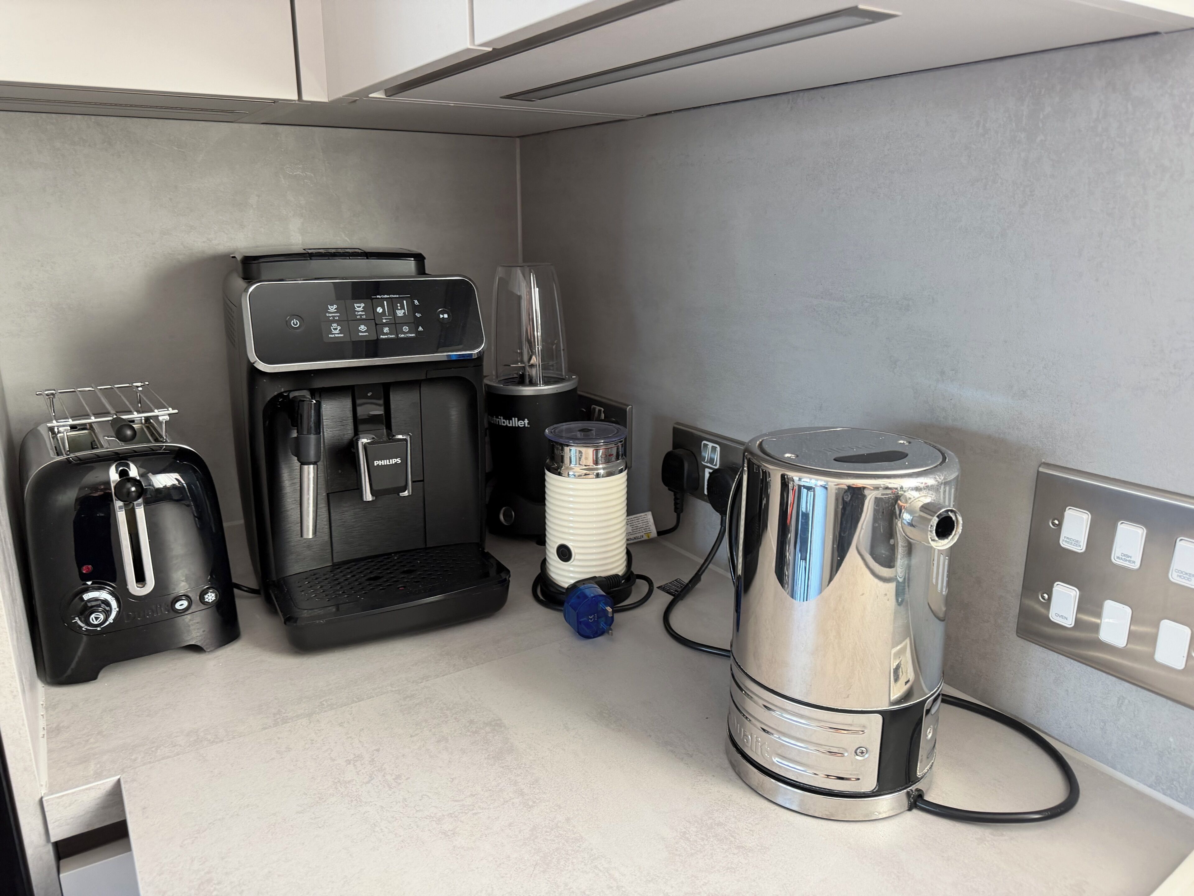 A kitchenette with a coffee maker, toaster, blender, and kettle.