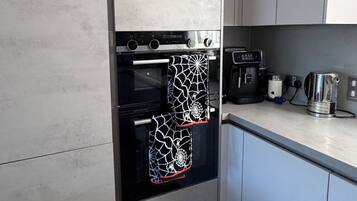 A kitchen with a built-in oven, a coffee maker, and a kettle on the countertop.