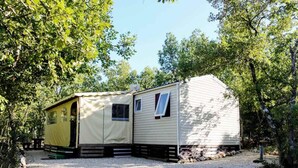 A mobile home with a covered porch and a separate sleeping area, surrounded by trees. - Cottage in a Natural Domain P10 (Saint-Privat-de-Champclos)