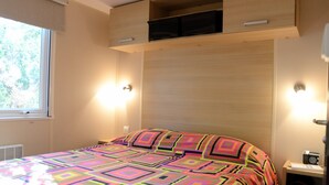 A bedroom with a bed, bedside tables, a window, and built-in storage. - Cottage in a Natural Domain P10 (Saint-Privat-de-Champclos)