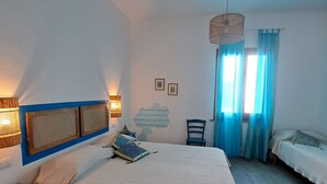 A bedroom with a large bed, a bedside table, a chair, a desk, and a window with curtains. - The scent of calicanto (Tresnuraghes)