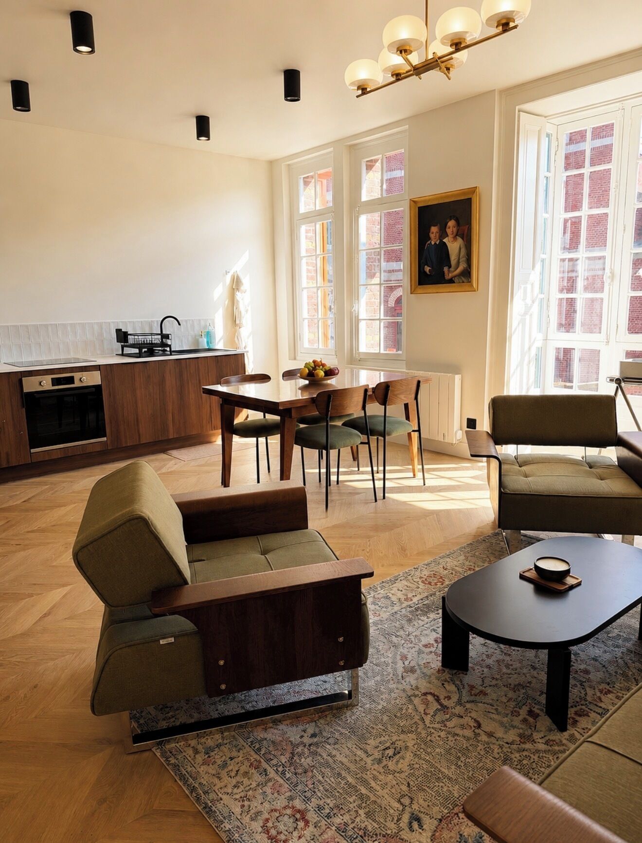 A modern living room with a dining area, kitchen, and large windows.