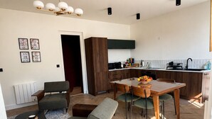 A modern living room with a dining area, a kitchen with wooden cabinets, and a radiator. - Belle Époque Villa - La Batelière - Bow Window - Ocean View - Exceptional (Mers-les-Bains)