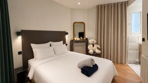 A hotel room with a bed, a bedside table, a mirror, a teddy bear, and a window with curtains. - Belle Époque Villa - La Batelière - Bow Window - Ocean View - Exceptional (Mers-les-Bains)