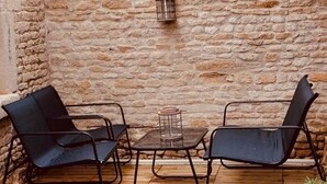 Un muro in pietra, un tavolo in metallo con sedie e una lanterna appesa.