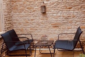 A stone wall, a metal table with chairs, and a hanging lantern. - Le Clos du Dan, a vacation rental near tourist attractions (Périers-sur-le-Dan)