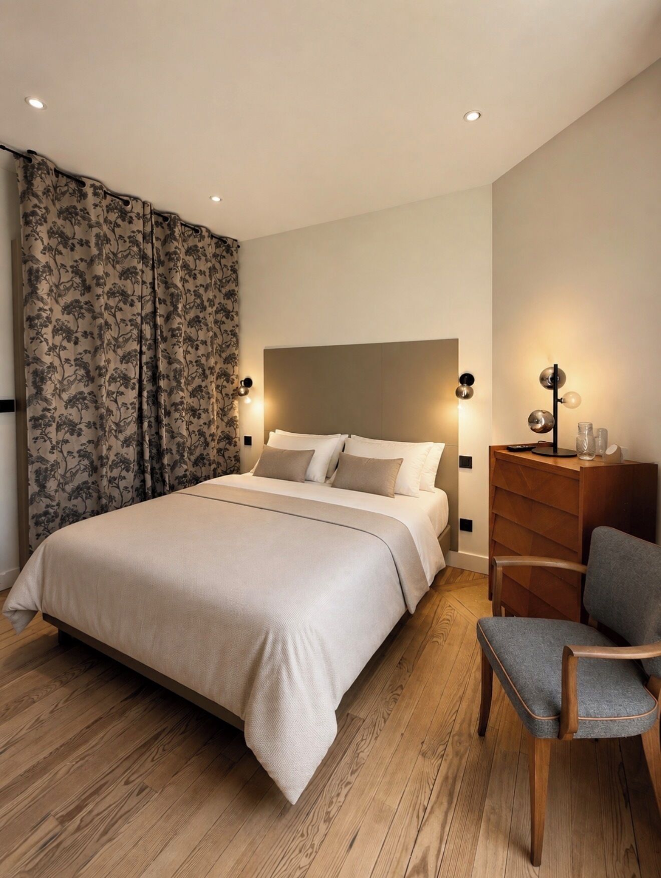 Una camera da letto con un letto, una cassettiera, una sedia e un comodino con lampade.