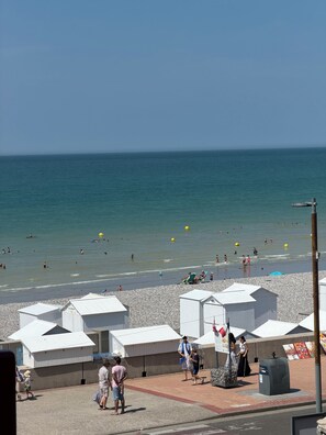 A beach with people swimming and sunbathing, white beach huts, and a clear sky. - VILLA BELLA - BELLE ÉPOQUE - BALCONY WITH OCEAN VIEW - EXCEPTIONAL - 20 METERS FROM THE BEACH (Mers-les-Bains)