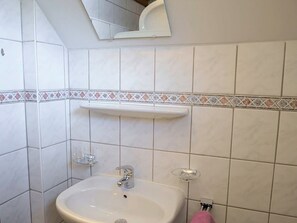Une salle de bain avec un lavabo, un miroir et des murs carrelés.