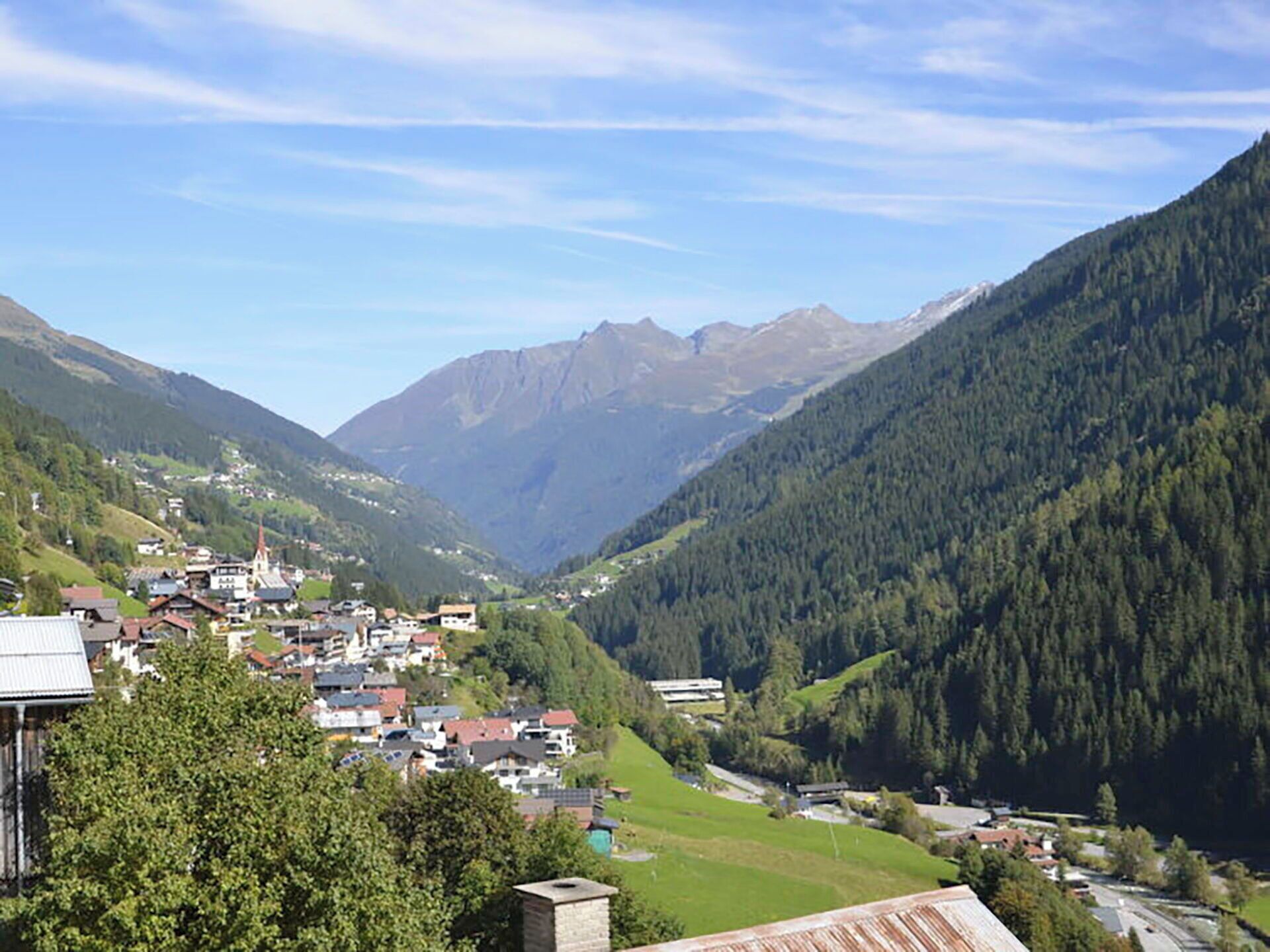 A valley with a small town, surrounded by mountains and dense forests.
