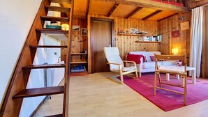 Ein Holzinterieur mit einer Treppe, einem weißen Sofa, einem roten Teppich und einem Holztisch.
