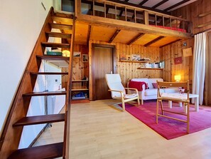 Ein Holzinterieur mit einer Treppe, einem weißen Sofa, einem roten Teppich und einem Holztisch.