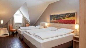 A hotel room with a sloped ceiling, a bed with white linens, a painting of a landscape, and a small table with a chair. - 1 Person Holiday Park Home in Herrenberg (Herrenberg)