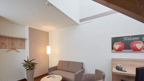 A modern room with a sofa, a small round table, a potted plant, and a wall-mounted shelf. - 1 Person Holiday Park Home in Herrenberg (Herrenberg)