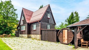 Ein traditionelles Holzhaus mit Steinunterbau, einer Metallbedachung und einem angebauten Holzfass.