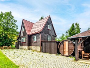 Ett traditionellt trähus med en grund av sten, ett tak av metall och en trätunna som sitter fast på sidan.