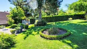 Un jardin bien entretenu, avec une grande variété de plantes et un parterre floral circulaire.