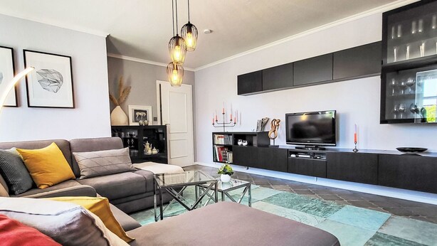 Un salon moderne avec un canapé, une table basse et un téléviseur à écran plat.