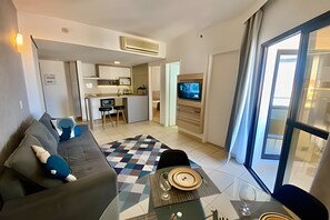 A modern living room with a sofa, a coffee table, and a TV mounted on the wall. - SHB Flat beira-mar no Gonzaga (Santos)