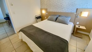 Een hotelkamer met een bed, nachtkastjes, een stoel en een bureau.
