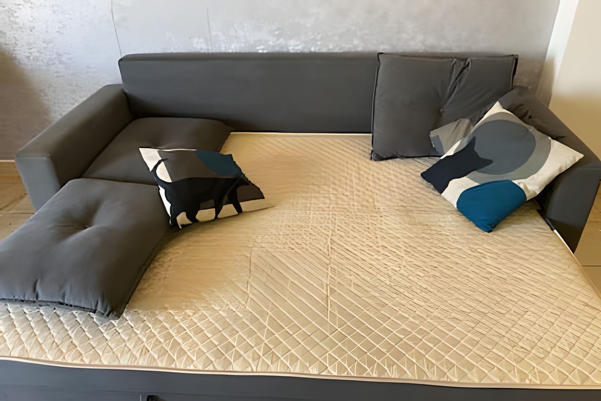 Um sofá modular com capa bege acolchoada e várias almofadas em tons de cinza e azul.